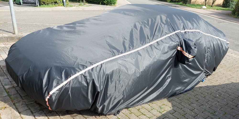 Ein Auto, das vollständig unter einer grauen Plane verborgen ist