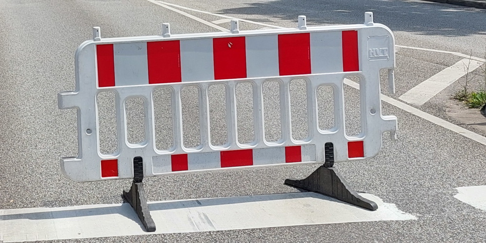 Weiße Absperrschranke mit roten Reflexstreifen auf einer Straße
